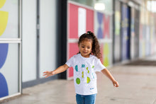 Load image into Gallery viewer, Child is wearing a white top with cactus shapes and blue jeans. 
