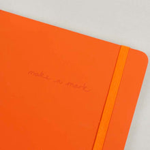 Load image into Gallery viewer, Close up of top right of orange notebook. &#39;make a mark&#39; engraving and elastic band can be seen.
