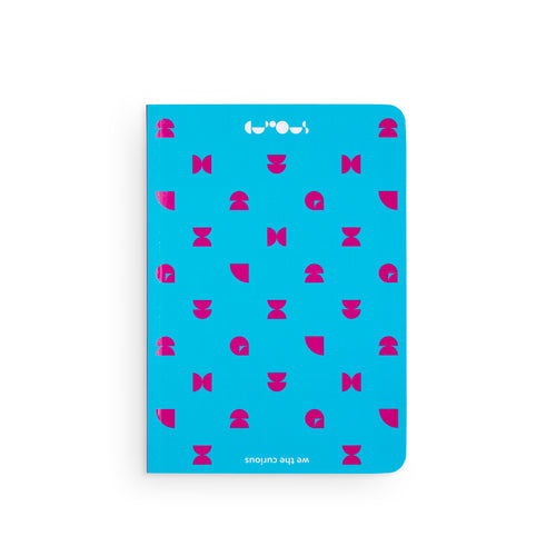 Bright blue notebook shows magenta pattern on top. At the top of the notebook is the We The Curious logo in white, and at the bottom is the name 