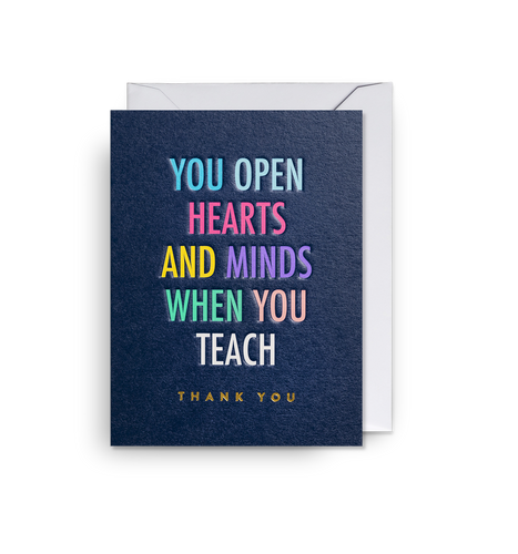 Dark blue card reads 'you open hearts and minds when you teach, thank you' in different colours. Card sits on white envelope. 