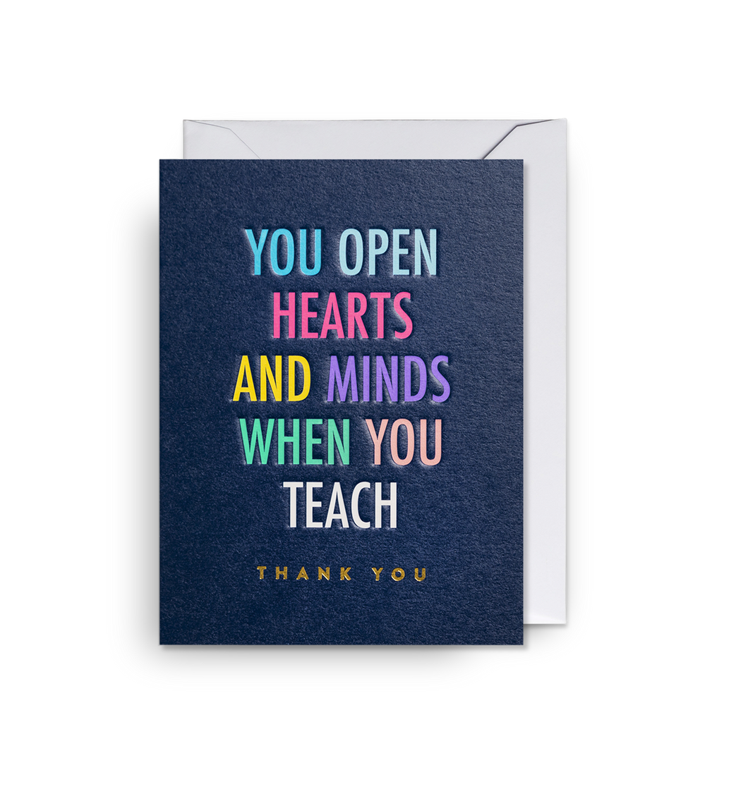 Dark blue card reads 'you open hearts and minds when you teach, thank you' in different colours. Card sits on white envelope. 