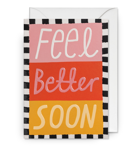 Pink, red and yellow card with black and white border. Large letters read 'feel better soon'. Card sits on white envelope.