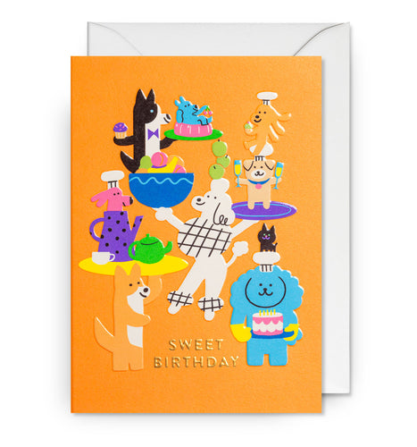 Orange card with dogs all standing and holding food and drinks. In gold foil, card reads 'sweet birthday'. 