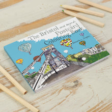 Load image into Gallery viewer, Colouring book laid flat on table with colouring pencils. Cover shows image of toll bridge.
