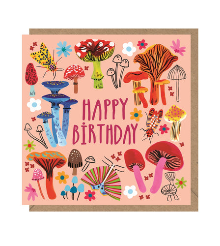 Pink card with illustrations of different types of mushrooms and two flying insects. Card reads 'happy birthday in pink letters' and sits on a brown envelope. 