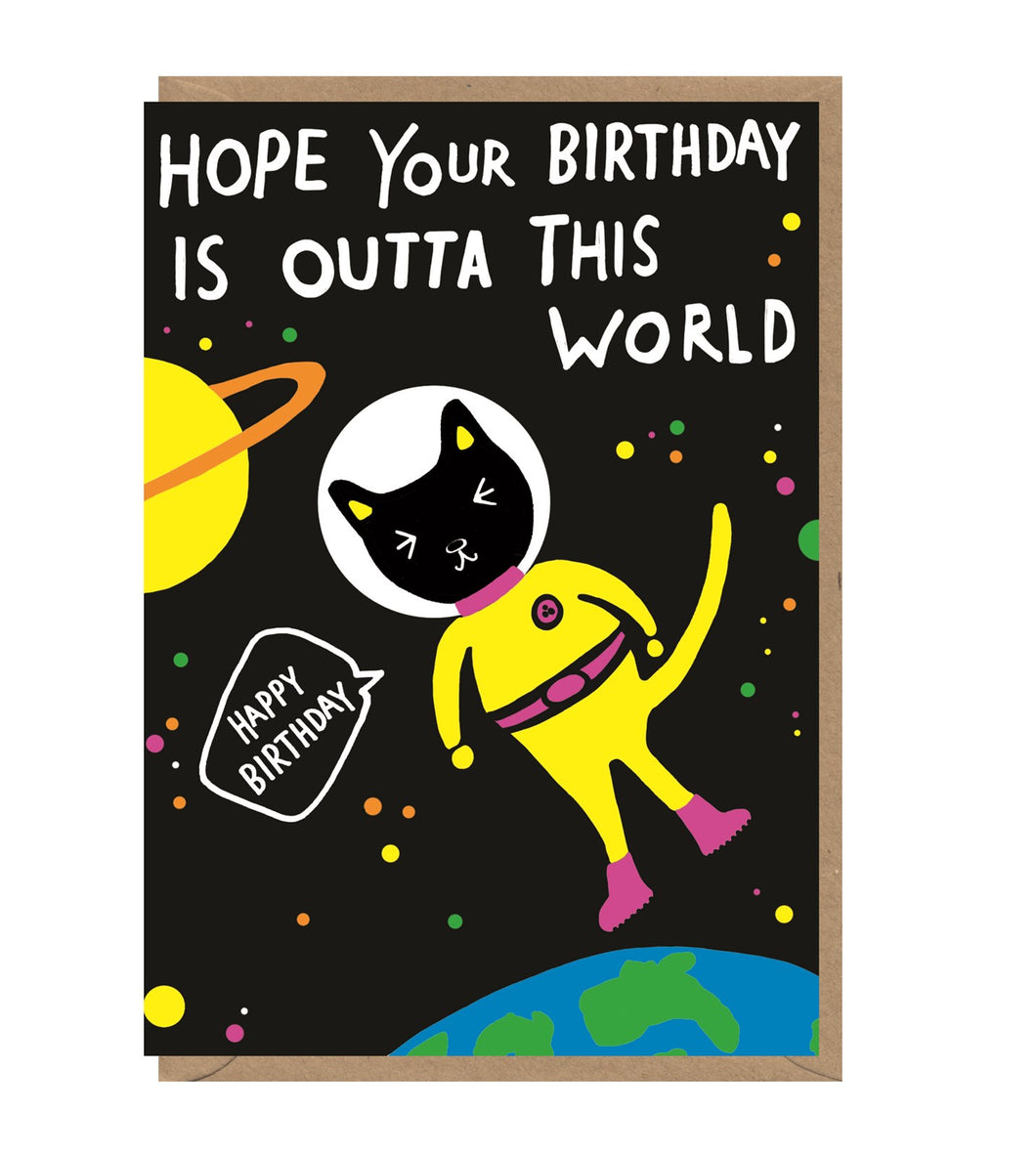 Black card with an illustration of a cat in a space suit floating above the earth. 'Hope your birthday is outta this world' is written in white capital letters. The cat has a speech bubble reading 'happy birthday'.  Card sits on brown envelope. 