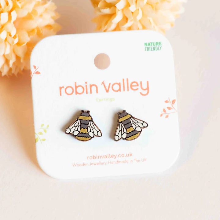 Bee-shaped earrings on a 'Robin Valley' branded card with decorative flowers in the background.