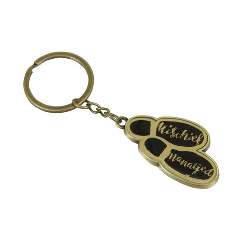 Keyring has gold coloured metal footprints with black soles and 'mischief managed' written in gold script letters. Chain and loop are also gold coloured. 