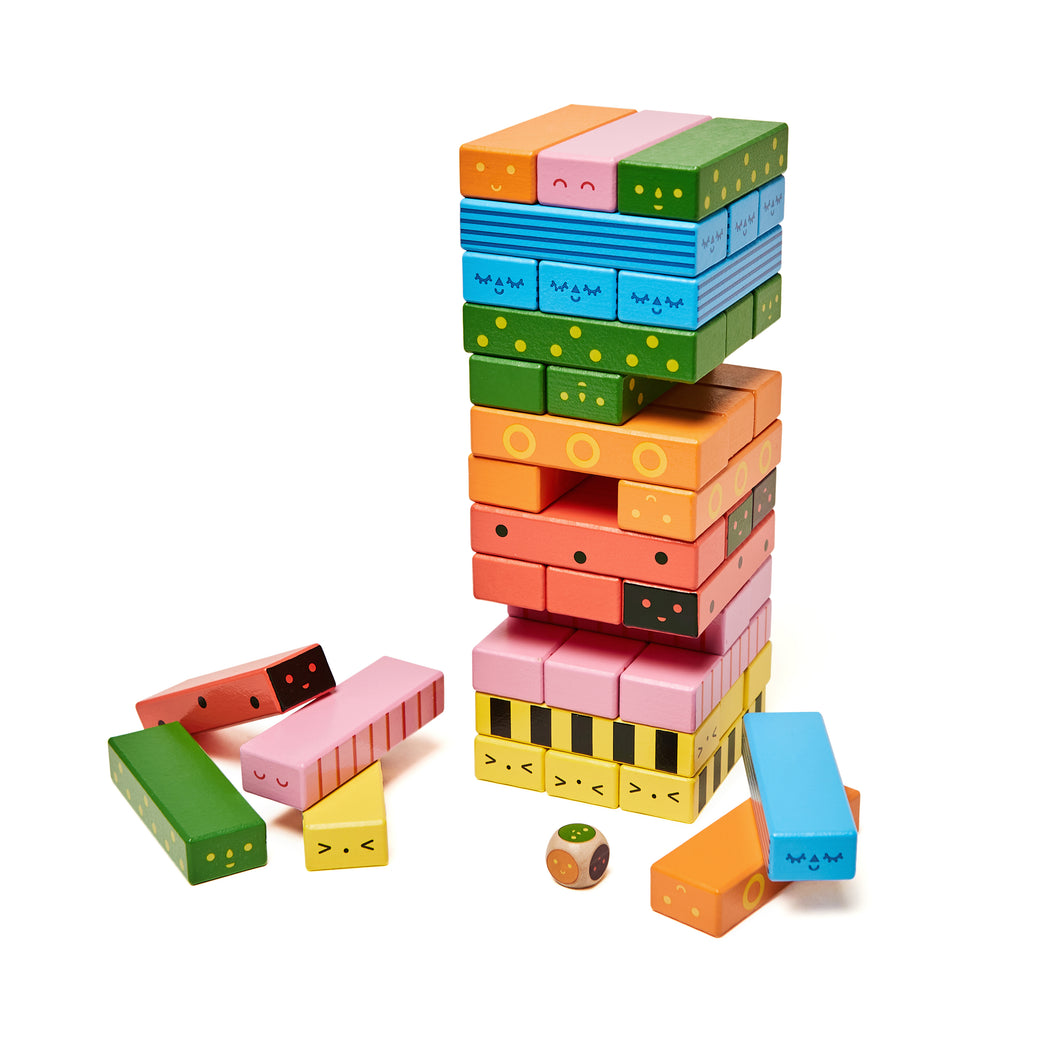 Colourful blocks stacked into a tower. Several different colours with each colour having a different smiley face pattern. A small die sits in front of the tower.