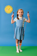 Load image into Gallery viewer, Light-skinned young girl with blonde hair and a dress holds the skipping rope while standing on the end. 
