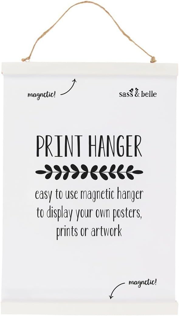 White pieces of wood with a brown string attached to two metal holes on the top. White poster inside reads 'magnetic, sass&belle, Print hanger, easy to use magnetic hanger to display your own powers, prints or artwork.' 