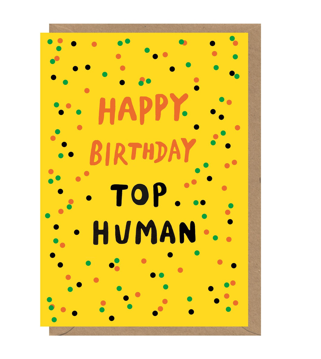 Yellow card with colourful polka dots. 'happy birthday top human' is written in orange and black ink. Card sits on brown envelope. 