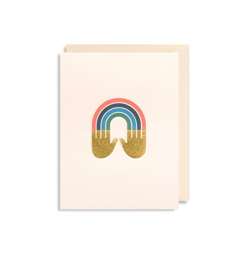 white card with cream envelope tucked inside. Gold hands with a rainbow streaming out of the fingers.