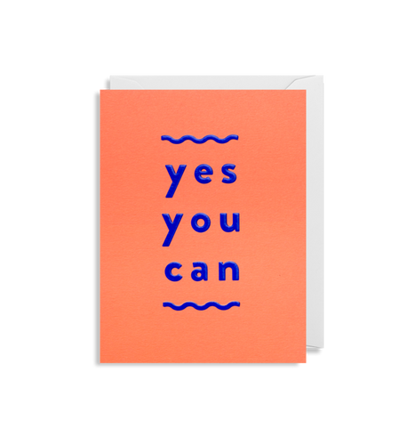 Orange card with white envelope tucked inside. Metallic blue lower case letters read 'yes you can' - each word under the last. Above and below the words are wavy blue horizontal lines. 