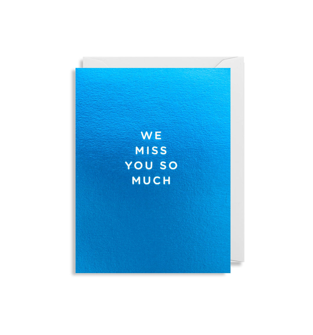 Metallic blue card with white envelope tucked in. In white capital letters, the card reads 'we miss you so much'
