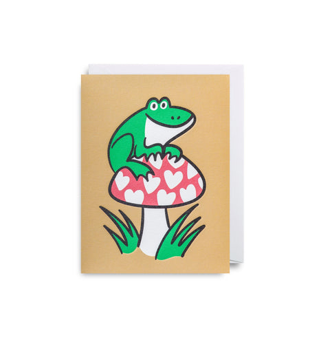 Muted yellow card with a white envelope tucked in. A green toad sits on top of a red mushroom with white hearts for spots.