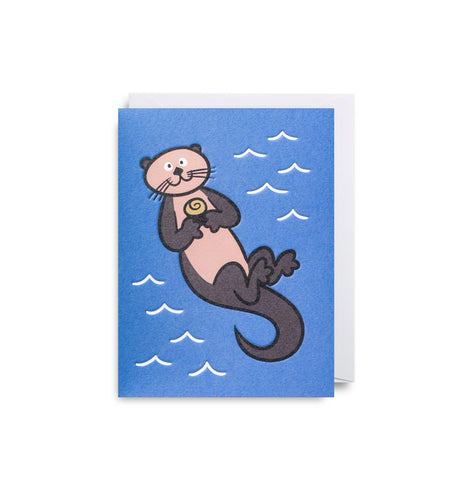 Blue card with illustration of otter floating on it's back in water. It holds a stone in its arms against it's chest. A white envelope is tucked into the card.