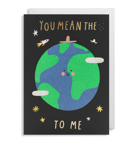 Black card with white envelope tucked inside. In gold foil capital letters, the card reads 'you mean the to me'. in between 'the' and 'to' is an illustrated, smiling world. There are little illustrations surrounding the earth of rockets, ufos, and stars.