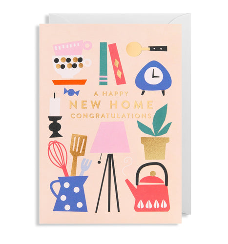 Off white card with white envelope tucked inside. Ilustrations of mugs, books, a clock, a plant, a lamp, a kettle, kitchen implements and a candle surround the words 'A Happy New Home congratulations' in gold foil capital letters.