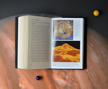 Load image into Gallery viewer, Open book and two balls (yellow and blue) rests on image of Jupiter. Book shows text on one page and two images and captions on the right. Top image is close up of Mercury, bottom image shows lava flow. 
