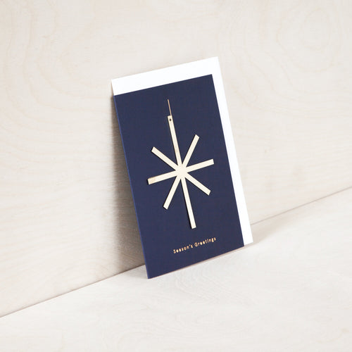 Blue card with brass star. Gold foil reads 