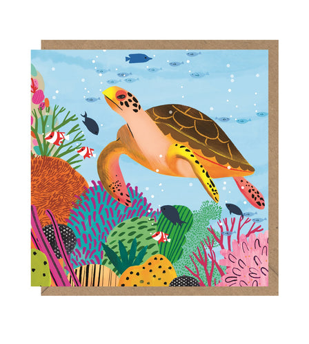 Square card with a brown kraft envelope tucked inside. Illustration of a turtle swimming above a coral reef with different types of fish. No words are on the card.