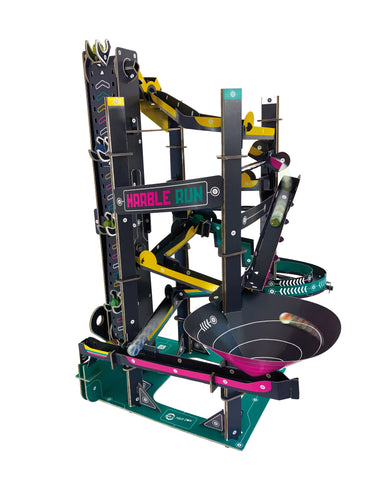 Fully assembled Marble Run is made of cardboard and is black, pink, green and yellow. It stands tall with a large funnel near the base.