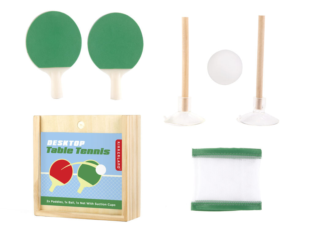 Kit contents include a wooden box, two green paddles, 2 sticks with suction cups, 1 white ball and a folded net with green border. Box reads 'desktop table tennis' with an illustration of paddles and a ball in front of a net.