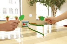 Load image into Gallery viewer, Image shows two light-coloured hands hitting the ball back and forth with paddles over a net on a table. 

