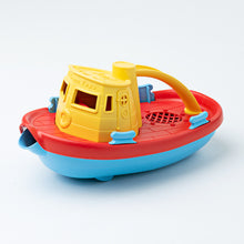 Load image into Gallery viewer, Angled view of Tugboat from side-front. Cabin and handle of tugboat are yellow, deck is red and base is blue. The front has a spout. 
