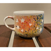 Load image into Gallery viewer, Painted mug with lots of colours with white spots in shape of hearts and stars.
