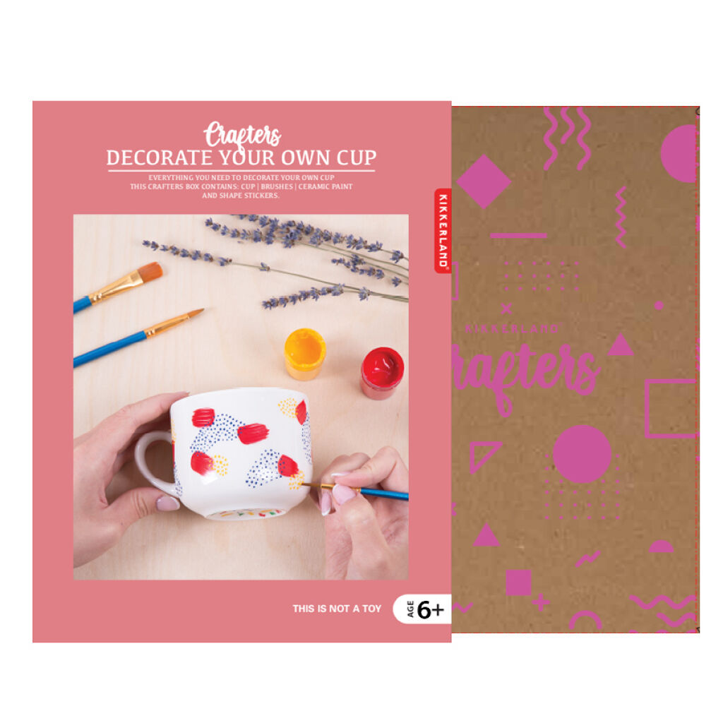 Packaging shows pink sleeve over a cardboard box. Photo on the sleeve shows light-skinned hands painting a mug using the brushes and paint.