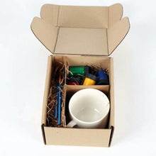 Load image into Gallery viewer, Inside contents of the box include white mug, pots of paint (red, yellow, blue, green) and brushes with blue handles (2 visible in photo).
