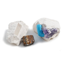 Load image into Gallery viewer, Two lumps of white block. Inside the one on the right are two gems, howlite and amethyst. Fallen out of the block on the left is a gold tiger&#39;s eye gem.
