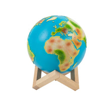 Load image into Gallery viewer, Earth lamp has light blue colour for seas, and the land is in green, brown and white to reflect the colours of each continent. Lamp sits on a wooden base.
