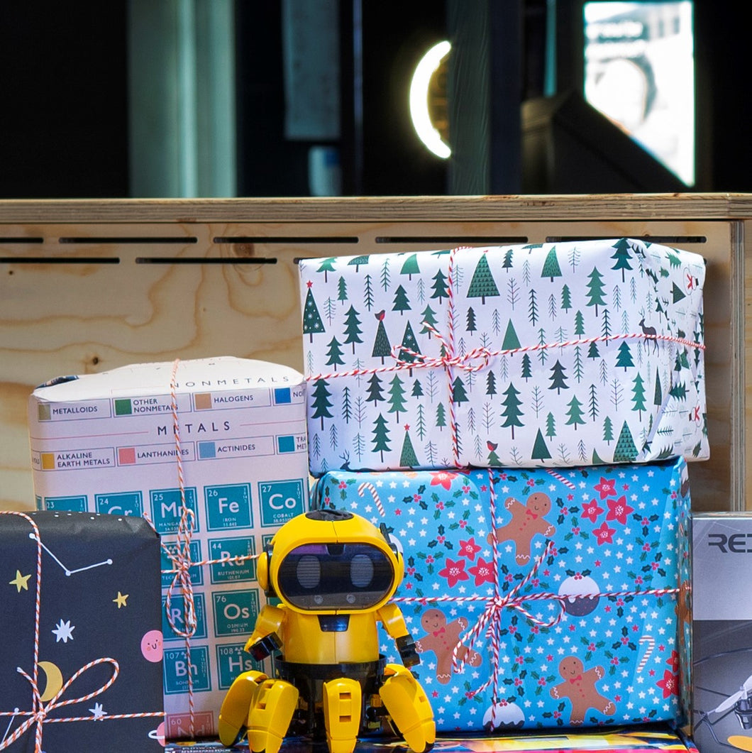 Wrapped presents with different gift wrap and string tied on top, with a Tobbie Robot toy in front. 