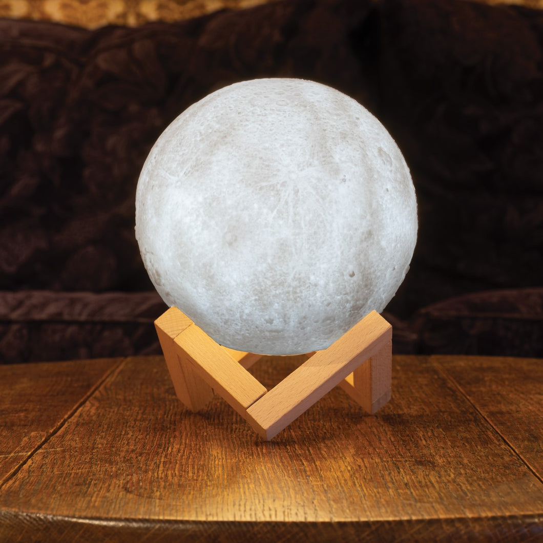 Moon light resting on wooden base on top of a table. Light shown is neutral setting.