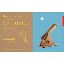 Load image into Gallery viewer, Catapult kit is packaged in cardboard box. Half of the box is uncoloured, while the other half is light blue, featuring a picture of the catapult in action. Box reads &quot;Newton&#39;s Lab Make Your Own Catapult. Learn about Newton&#39;s first law of inertia by making your own catapult. Discover the world of physics while playing.&quot; Brand on the side is Kikkerland.
