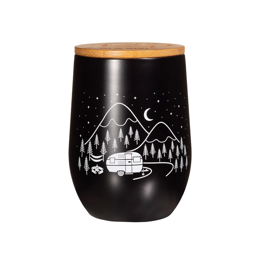 Black travel mug without handles. Bamboo lid. Design on mug shows a camper van parked in a forest with mountains in the background, and stars and moon in the sky.