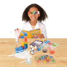 Load image into Gallery viewer, Medium-skinned girl with curly brown hair and brown skin sits at a table in a lab coat reading Rainbow Lab Book and other kit contents in front of them.
