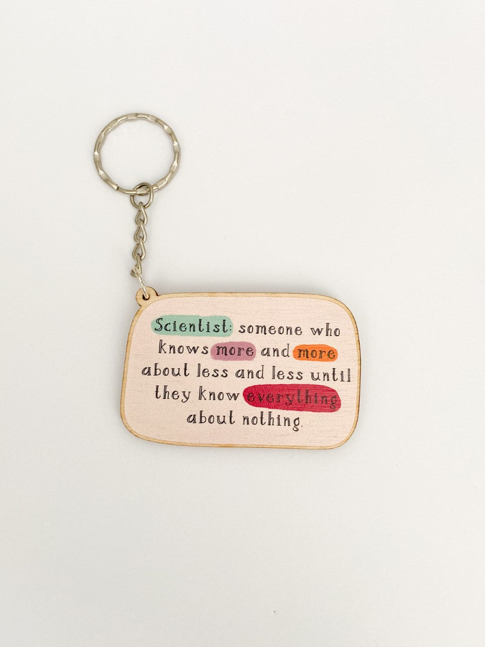 Keyring reads 'Scientist: someone who knows more and more about less and less until they know everything about nothing'. Words 'scientist', 'more' and 'everything' are highlighted. A small chain leads to a keyring attachment.
