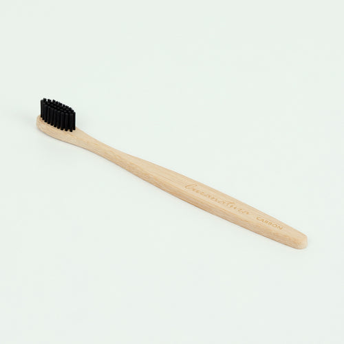 Bamboo toothbrush has black bristles. The wooden handle has the brand name 